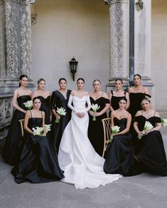 a group of women standing next to each other in black dresses and holding bouquets