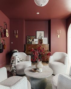 a living room filled with white furniture and red walls