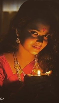 a woman holding a lit candle in her hand and looking at the camera with an evil look on her face