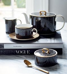 two coffee cups and saucers sitting on top of a book with spoons next to them