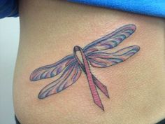 a woman's stomach with a tattoo of a dragonfly on the side and pink ribbon