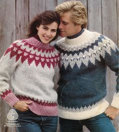 two people standing next to each other with their arms around each other wearing sweaters