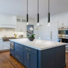 a large kitchen with white cabinets and blue island in front of the stove top oven