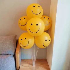 a bunch of yellow balloons with smiley faces on them sitting in front of a couch