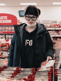 a woman wearing a face mask and gloves in a grocery store with plastic bags behind her