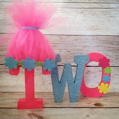 the word w is made out of wood and has pink tulle skirt on it