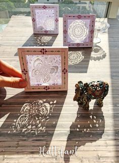 the shadow of a small elephant is cast on paper cutouts and placed on a wooden table