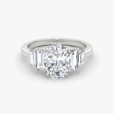 a three stone engagement ring with baguettes on the sides and an oval diamond in the center