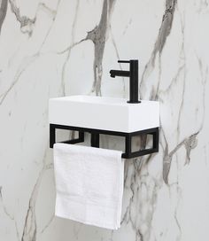 a white sink sitting next to a black faucet on top of a wall