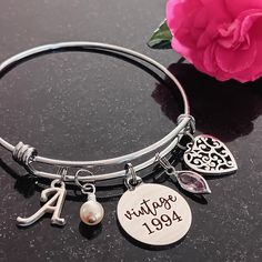 Celebrate her milestone birthday with this thoughtful 'vintage 1994' personalized 30th birthday bracelet. The stainless steel adjustable bangle bracelet has a 'vintage 1994', cream pearl, filigree heart, birthstone, and a script initial for personalization.  The bracelet comes beautifully packaged and ready to gift. Gift for Wife, Spouse, Girlfriend, Sister, Goddaughter, Granddaughter, Daughter, Niece, Family member, Cousin, Coworker, or Friend.  Gift from coworker, daughter, sister, mother, fri Classic Adjustable Charm Bracelet For Anniversary, Classic Adjustable Name Bracelet For Birthday, Vintage Adjustable Engraved Charm Bracelet, Vintage Adjustable Charm Bracelet With Engraving, Vintage Nickel-free Bracelets For Anniversary, Personalized Vintage Jewelry For Birthday, Vintage Personalized Jewelry For Birthday, Personalized Vintage Charm Bracelet Gift, Anniversary Name Bracelet With Birthstone