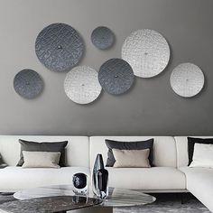 a living room filled with white furniture and lots of circles on the wall above it