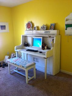 a white desk with a computer on top of it in front of a yellow wall