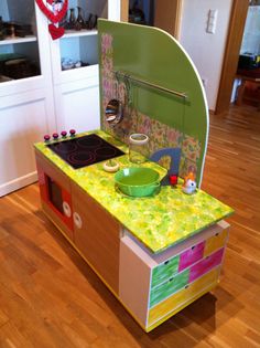 a child's play kitchen in the shape of a stove top oven with colorful counter tops