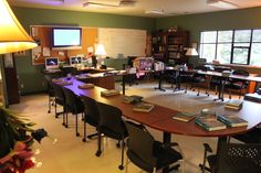 an empty classroom with desks and chairs in front of large windows on the wall