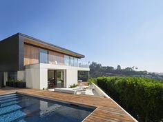 a house with a pool in front of it and an outside deck area next to it