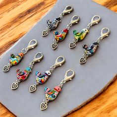 six pairs of keychains with different designs on them sitting on a wooden table