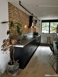 a kitchen with a brick wall and wooden flooring next to a dining room table