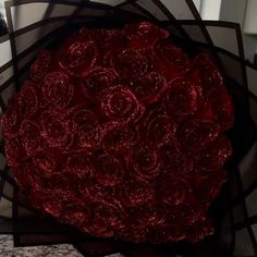 a red rose in a black box on a table with other items around it and a window behind it