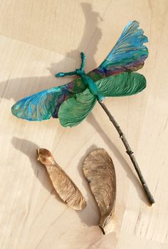 a blue dragonfly sitting on top of a wooden table next to a piece of wood