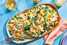 a large casserole dish filled with rice and vegetables on a blue tablecloth