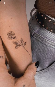 a woman's arm with a rose tattoo on it and another person holding her hand