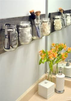 mason jars are lined up on the wall to hold makeup brushes and other personal care items