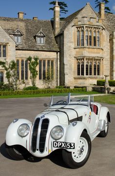 an old white car parked in front of a large building