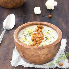 a wooden bowl filled with soup and garnished with croutons on top