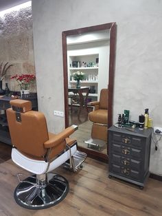 a salon chair sitting in front of a mirror on top of a hard wood floor