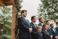 a group of men standing next to each other in front of a wooden gazebo