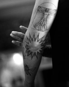 a person with a tattoo on their arm holding his hand up to the sunflower