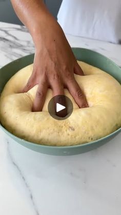 a person placing something on top of a doughnut in a blue bowl that is sitting on a counter