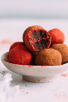 a white bowl filled with red and brown truffles on top of a table