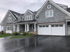 a large gray house with white trim and two garages on the side of it