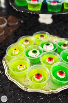 there are many cupcakes on the tray and one is green with red eyes