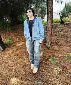 a young man standing in front of a tree