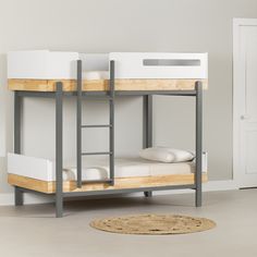 a bunk bed with two sets of mattresses on it and a rug next to it