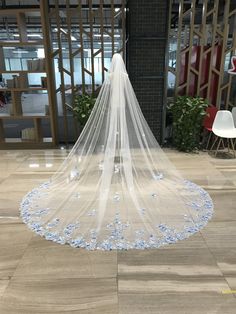 a wedding veil with blue flowers on the bottom is sitting in front of a chair