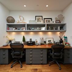 an office area with two desks, shelves and pictures on the wall above them