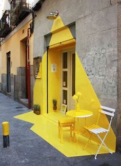 a yellow table and chairs in front of a building