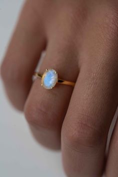 a woman's hand wearing a ring with a white opal stone on it