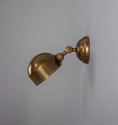 an antique brass wall light on a white wall in a room with grey walls and flooring