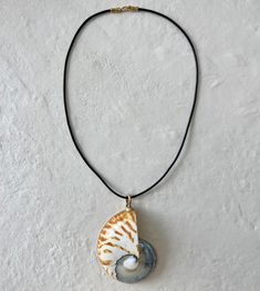 NAUTILUS SEA SHELL is a symbol of nature's grace in growth, expansion, and renewal. Known for deflecting negative energies, the Nautilus also purifies the surrounding space and attracts loving energies. The shell may be used to assist in meditation and invokes calmness, provides strength, balance and renews the physical energy. - Black Solid Leather Cord Gold Filled Clasp 3" Nautilus Sea Shell 20" Length House of Olia is committed to utilizing only sustainable leather sources in all it's product Adjustable Shell-shaped Unique Necklace, Adjustable Ocean-inspired Shell Pendant Necklace, Adjustable Bohemian Shell-shaped Necklace, Bohemian Adjustable Shell-shaped Necklace, Adjustable Natural Color Shell-shaped Necklace, The Nautilus, Sustainable Leather, Black Solid, Nautilus