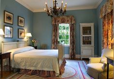 a bedroom with blue walls and white bedding has a chandelier hanging from the ceiling