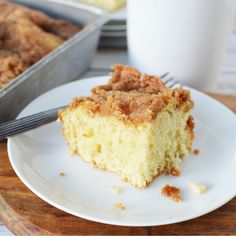 a piece of cake sitting on top of a white plate next to a cup of coffee