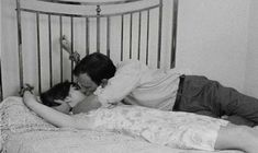 a man and woman laying in bed with their arms around each other as they kiss