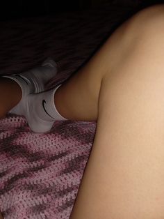 a woman laying on top of a bed with her legs spread out and wearing socks