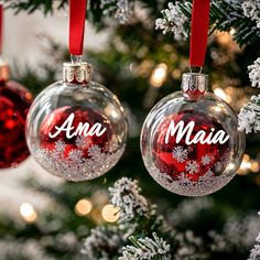 two ornaments hanging from a christmas tree with the word ama written on one ornament