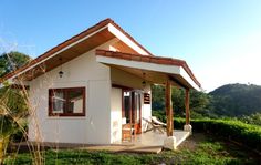 a small white house sitting in the middle of a lush green field with palm trees