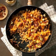 a pan filled with food sitting on top of a table next to a wooden spatula